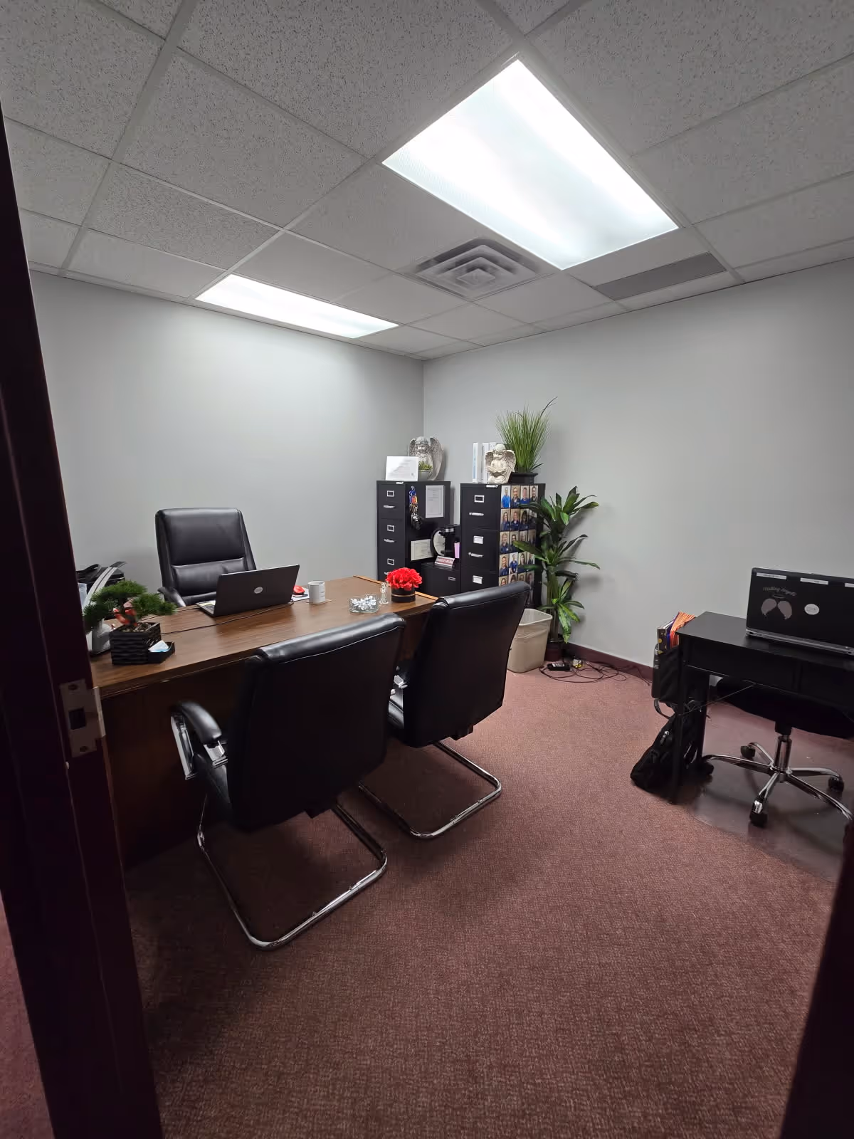 Office in a senior care facility with desk, chairs, cabinets, and plants.