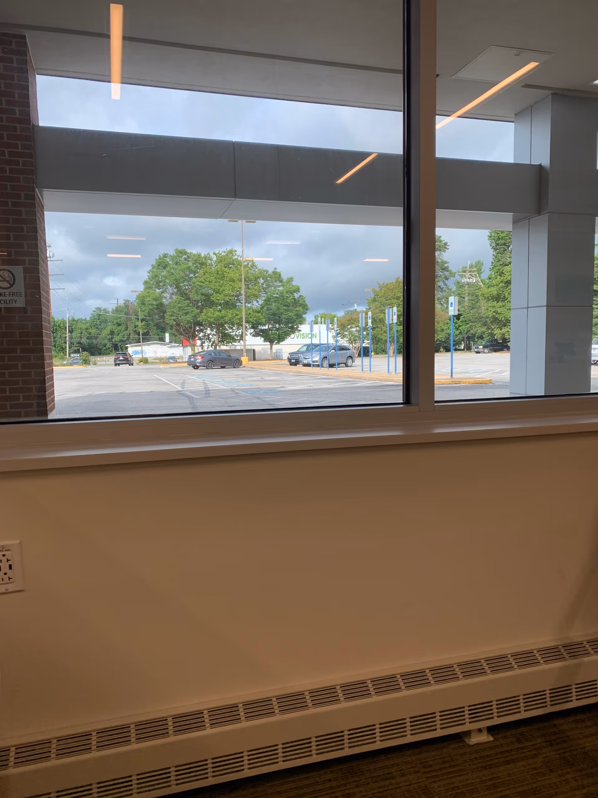 Interior corridor with a large window showing a parking lot and trees outside.