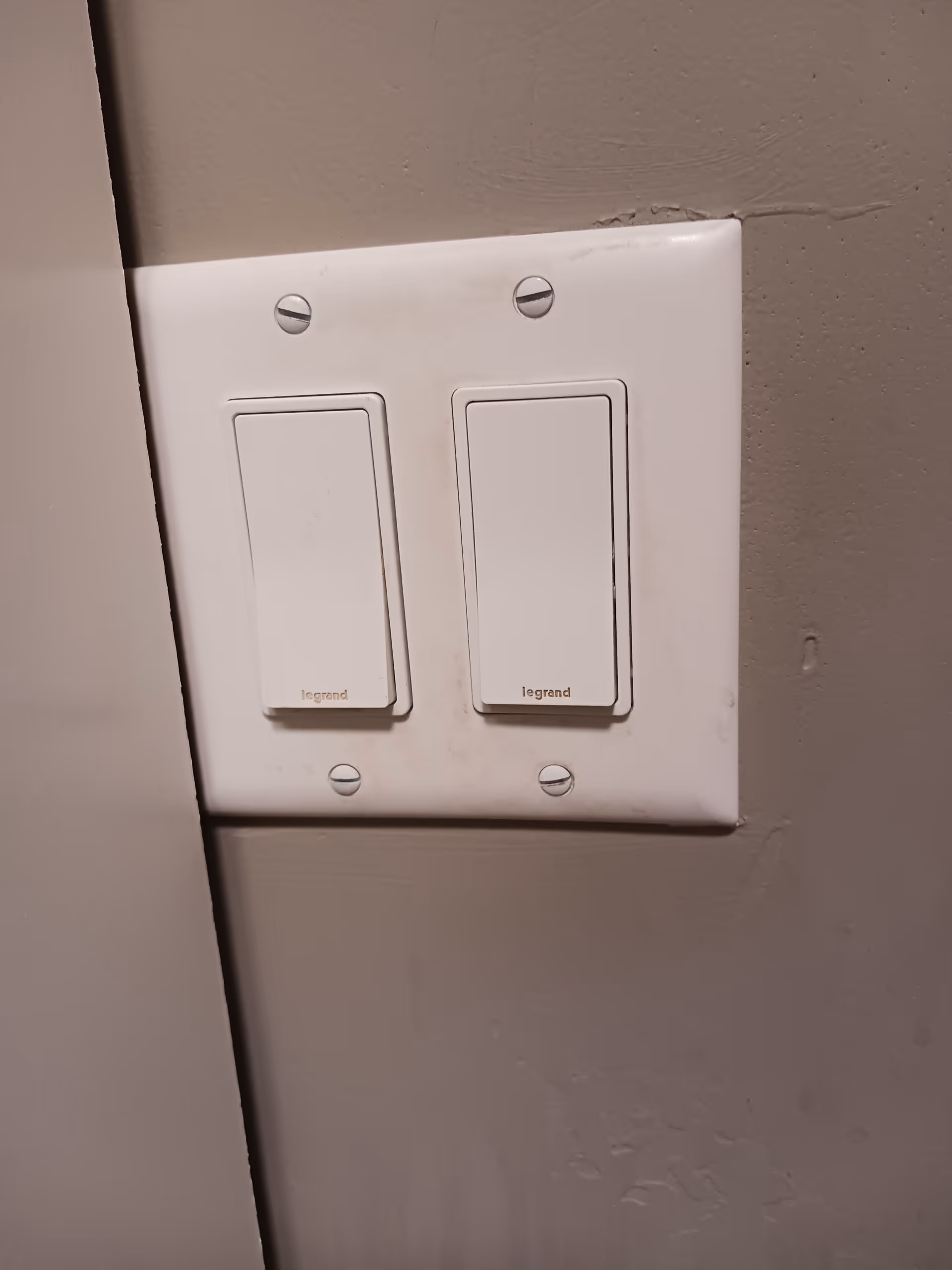 White double light switch on a gray wall in a senior living facility hallway.