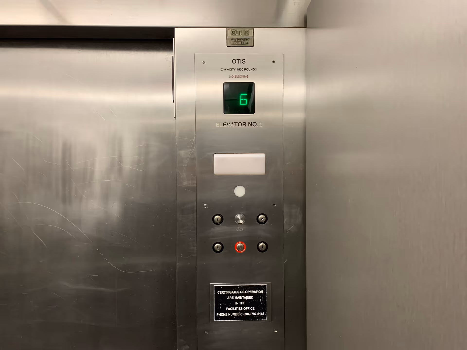 Elevator interior with a floor indicator showing six on a metal panel