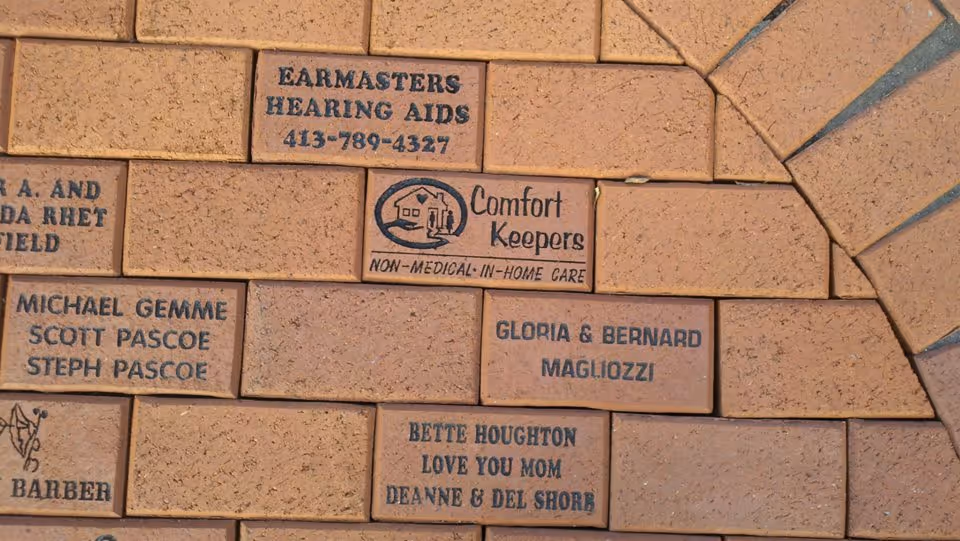 Brick wall with engraved name bricks, including 'Comfort Keepers' logo and donors' names.