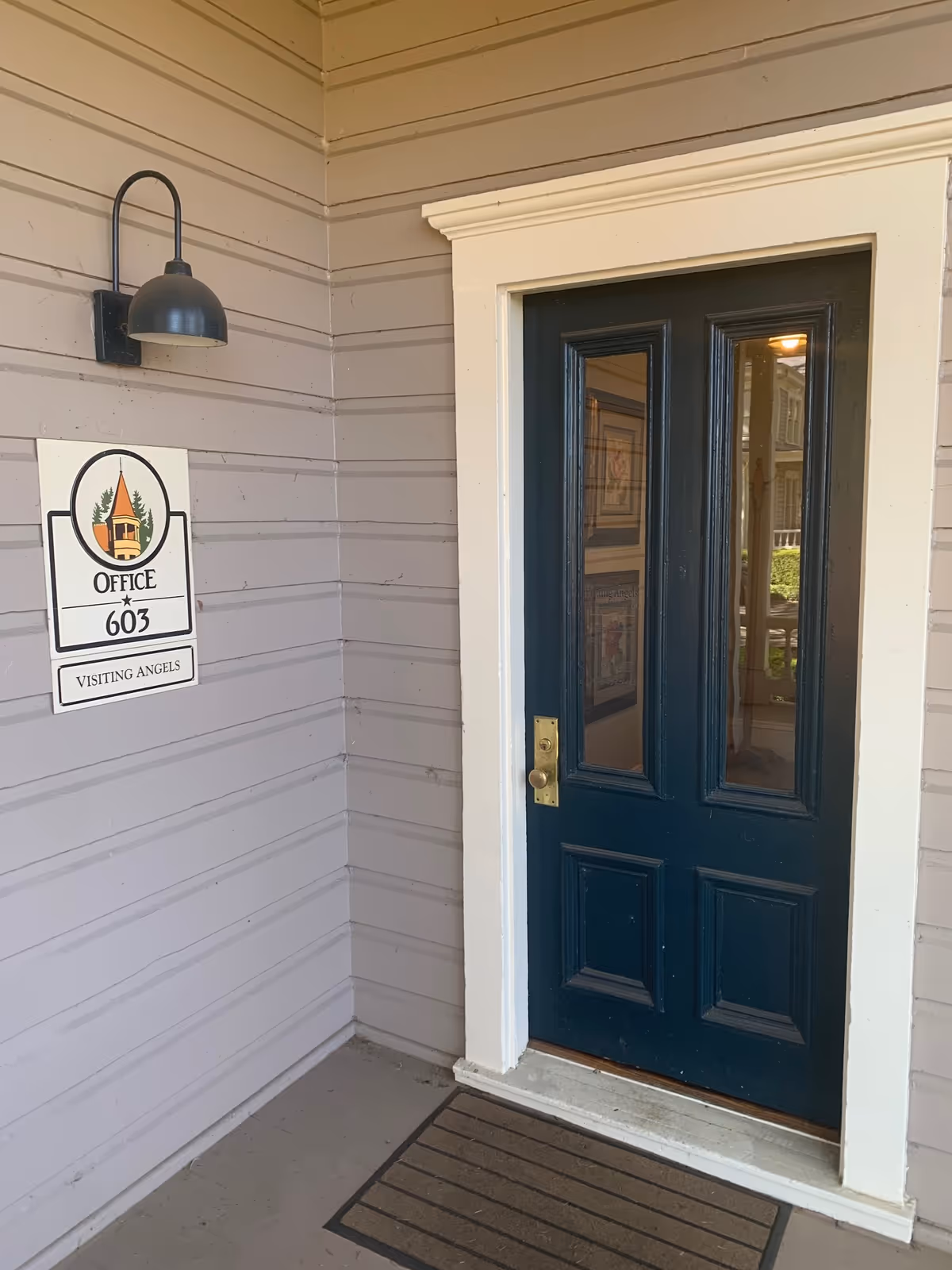 Exterior entrance of a senior care office with a dark blue door and Visiting Angels sign