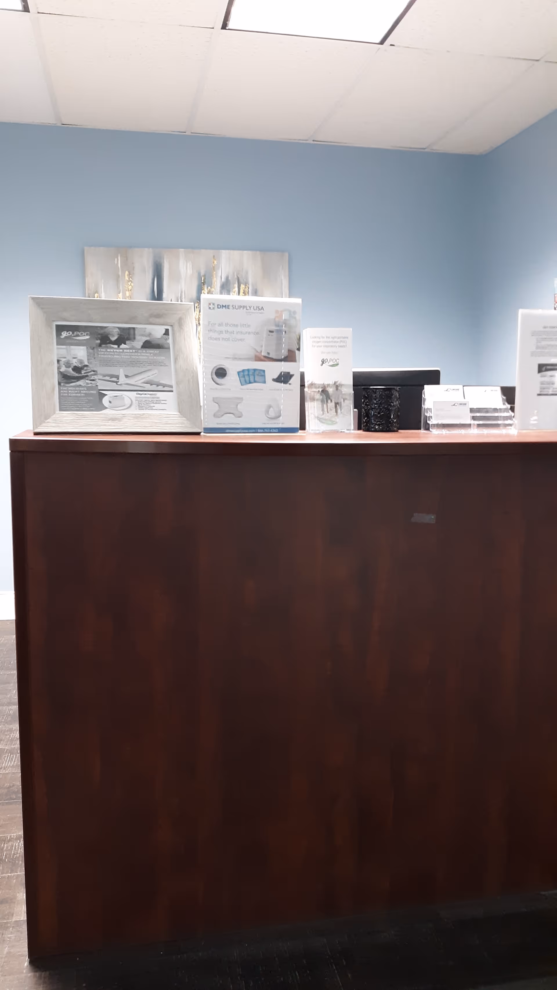 Reception desk with brochures against a light blue wall in a lobby.