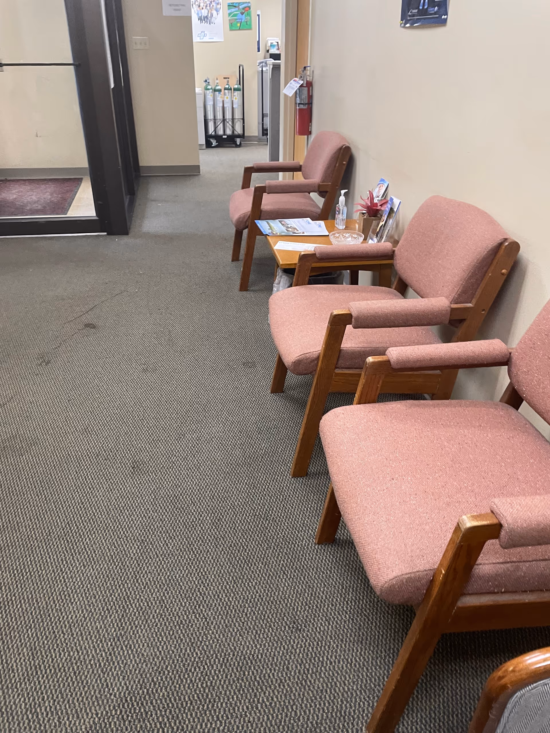 A hallway seating area with pink upholstered chairs and a small table in a senior facility.