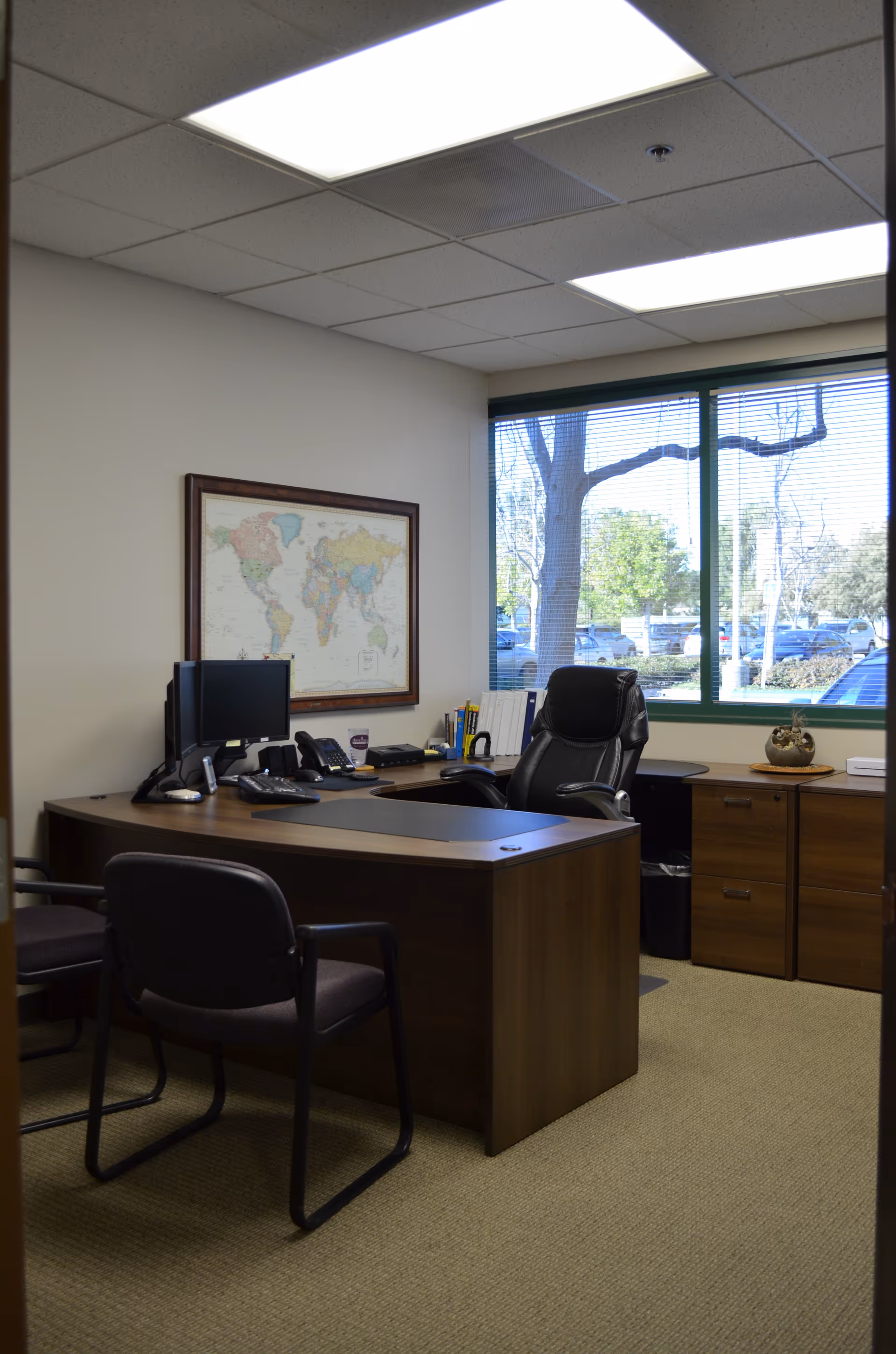 Administrative office with desk, chairs, a wall map, and a large window.