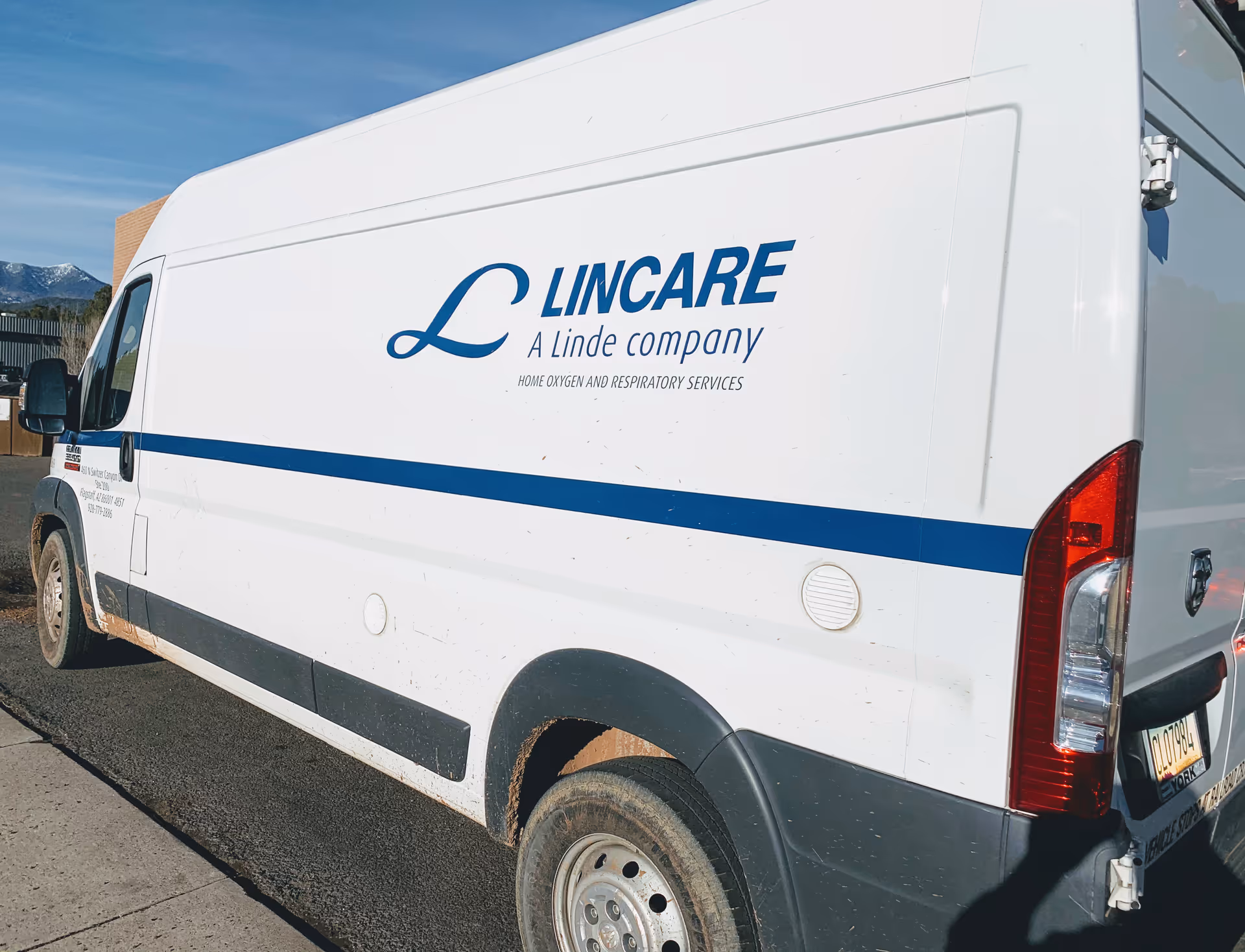White LINCARE van with blue logo parked outdoors beside a facility.