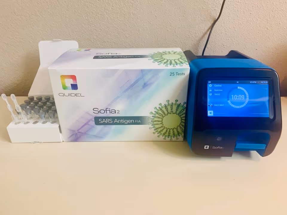 Sofia SARS test kit box and blue Sofia reader on a clinic counter.