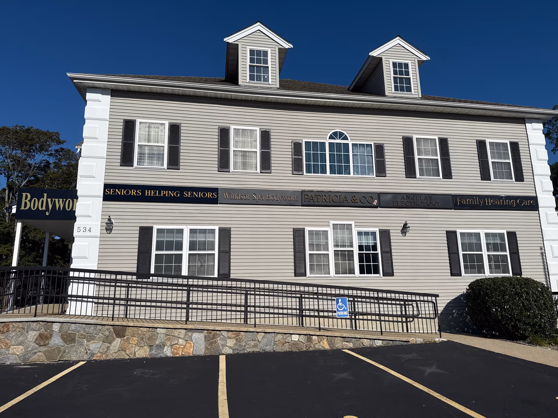 Two-story beige building with multiple windows and a row of senior care signs