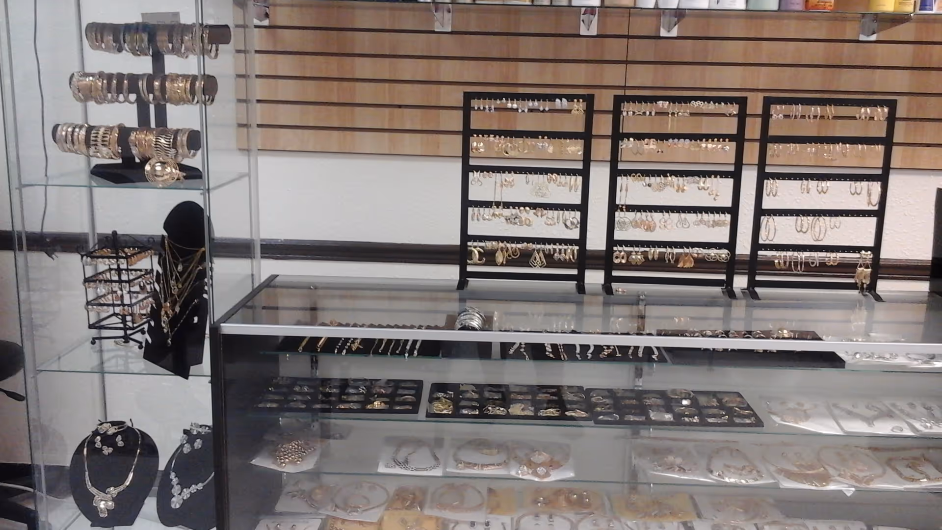 Jewelry display with bracelets, necklaces, and rings arranged on racks and glass cases.