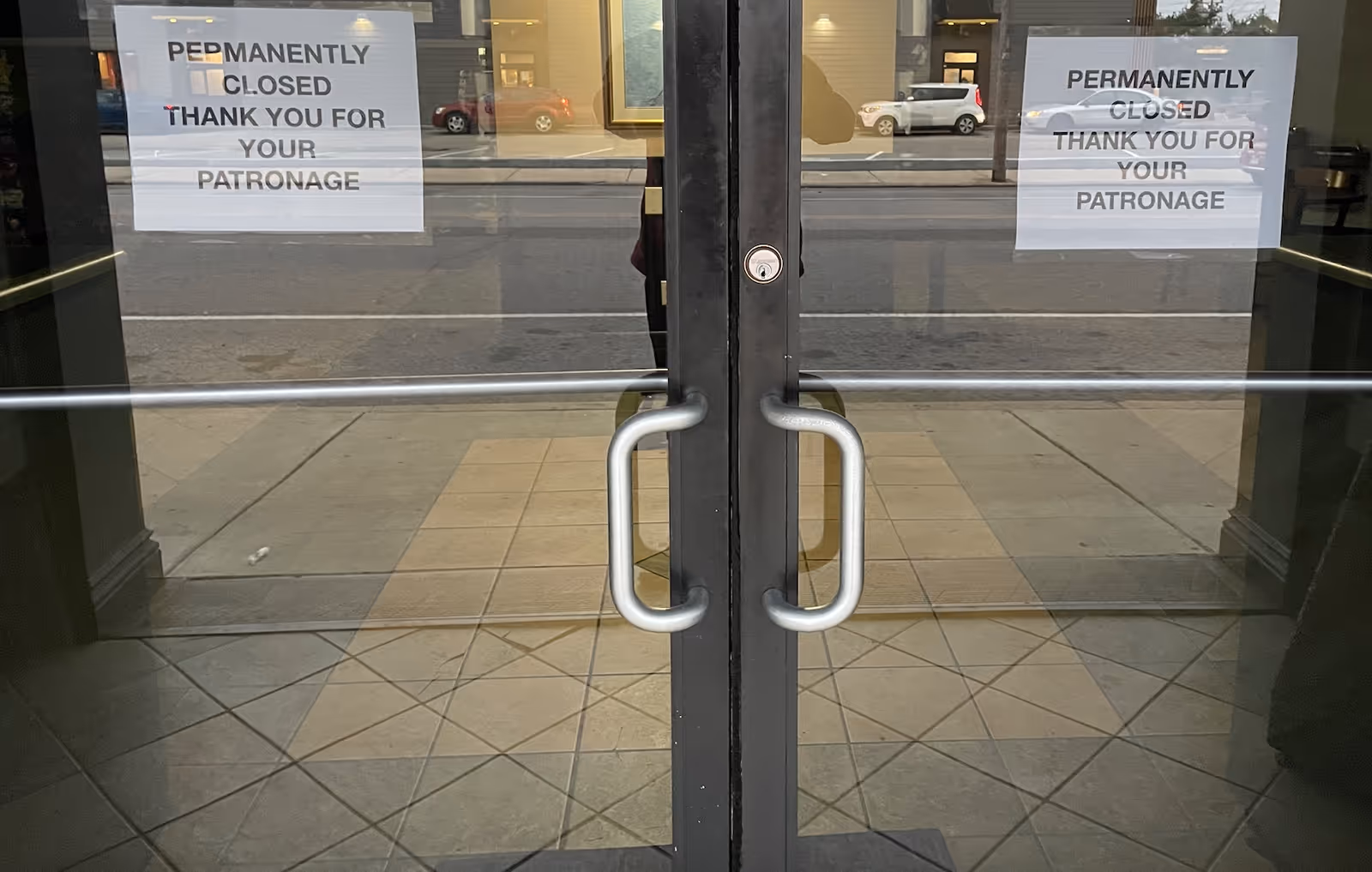 Double glass doors with metal handles and 'Permanently Closed' signs at a building entrance.