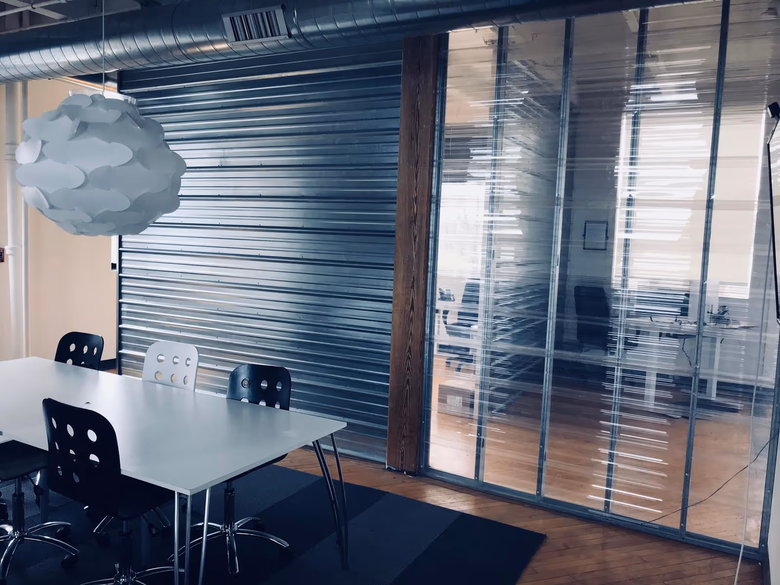 A modern meeting area with a white table, black and white chairs, and glass partition.