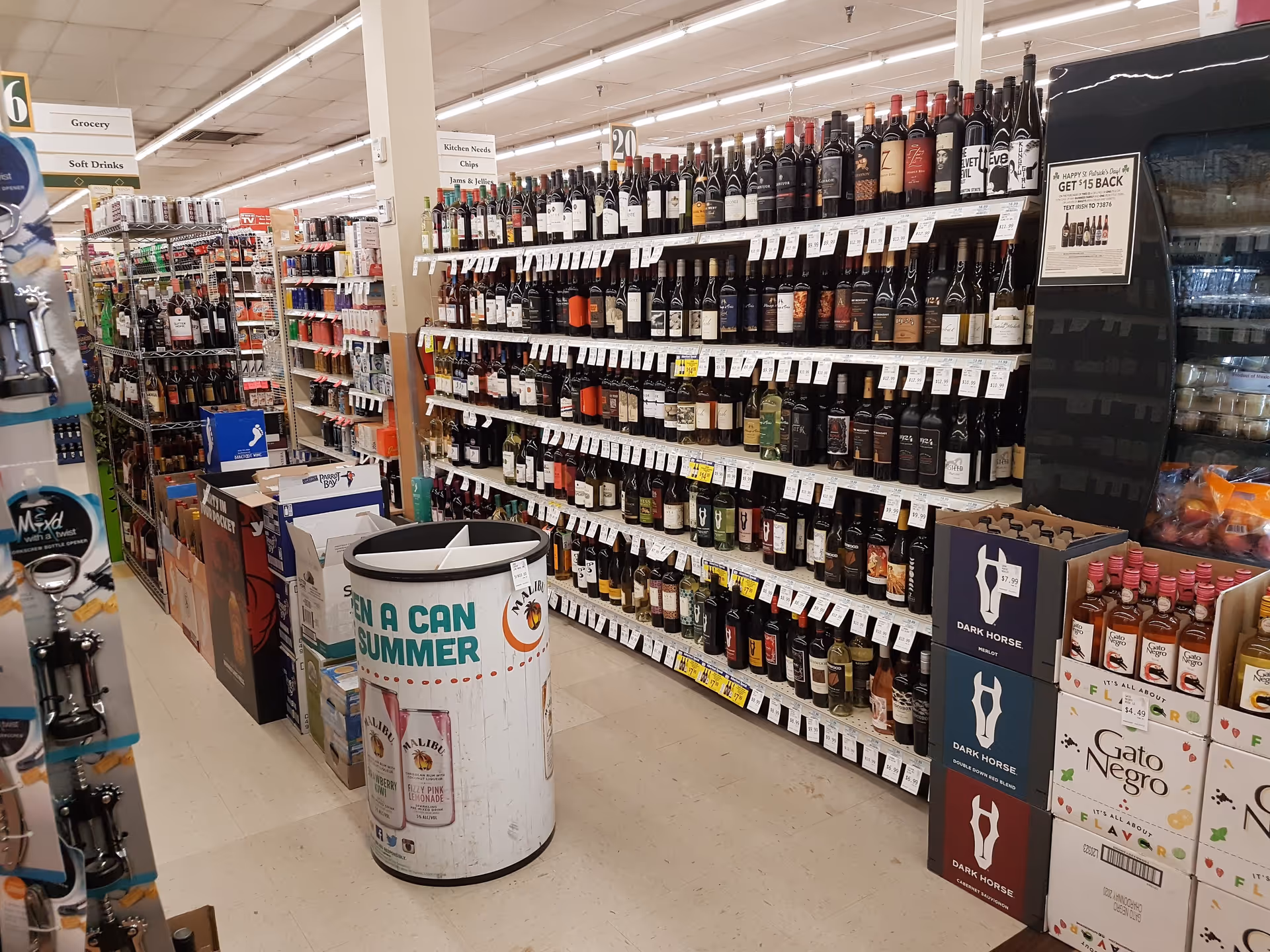 An aisle of Discount Drug Mart stocked with wine bottles on shelves and a circular display.