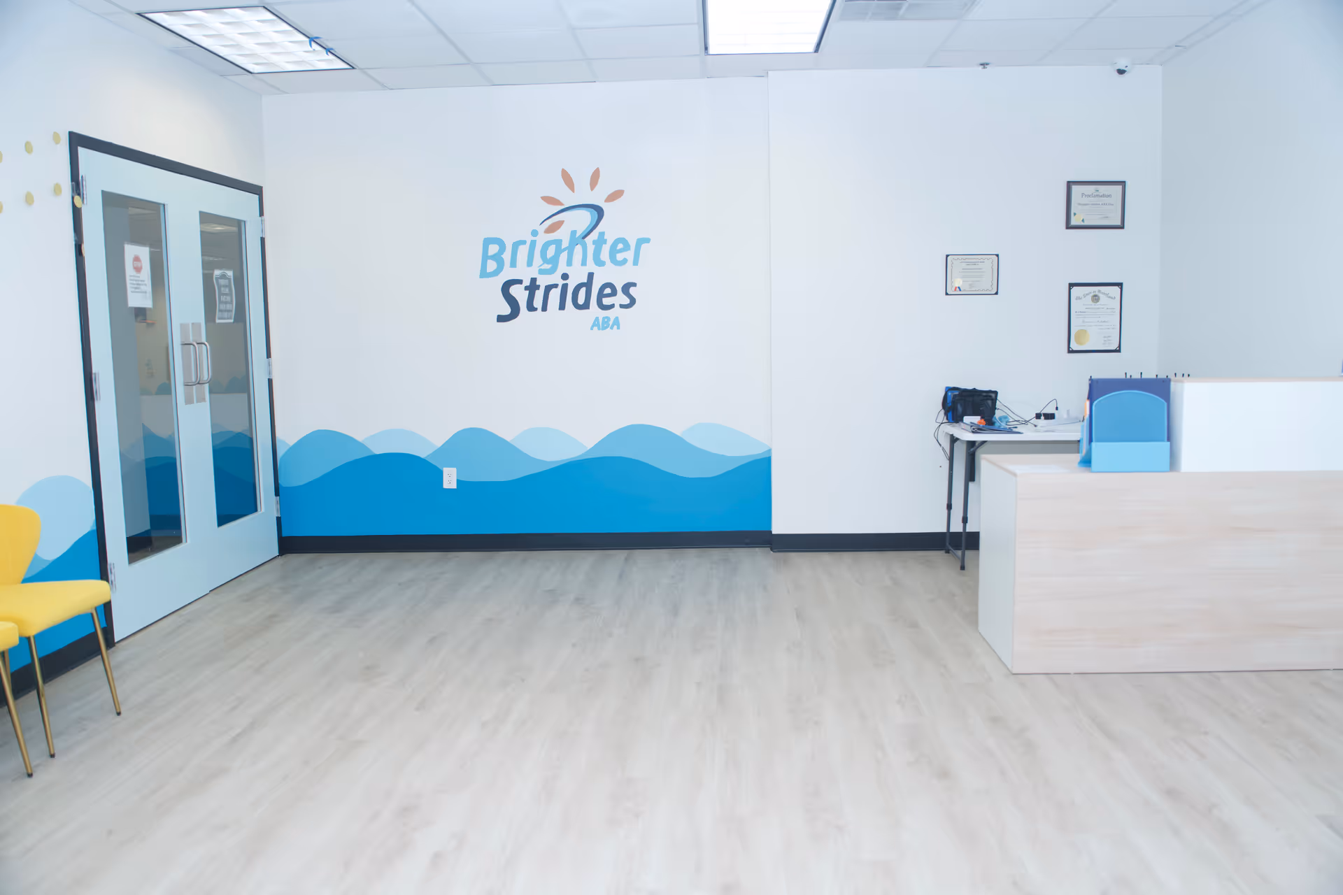 Reception area featuring Brighter Strides ABA Therapy logo on white wall near a desk.